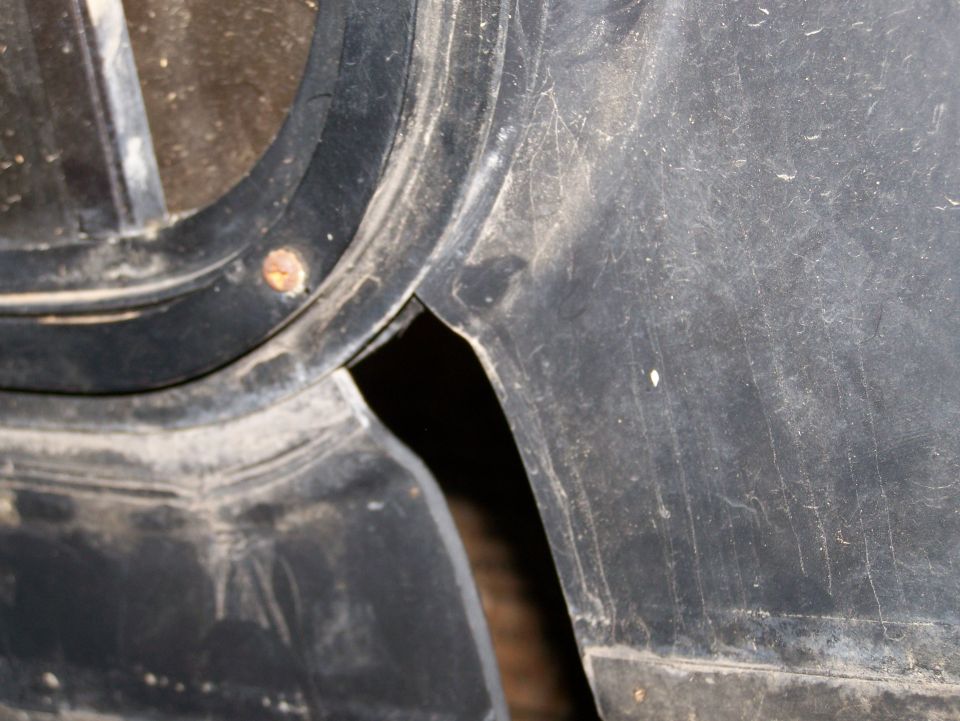 Close-up of a dusty black plastic vehicle fender flare with a screw.