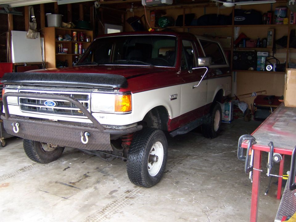 Lifted two-tone red and white Ford Bronco parked in a garage