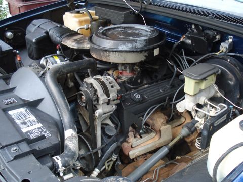 1984 Jeep J-10 - The engine bay of a vehicle, showing various mechanical parts and hoses.