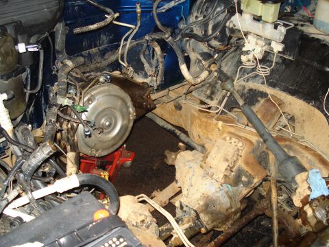 1984 Jeep J-10 - The engine bay of a vehicle is shown, with the transmission and torque converter prominently displayed. Various hoses, wires, and the brake…