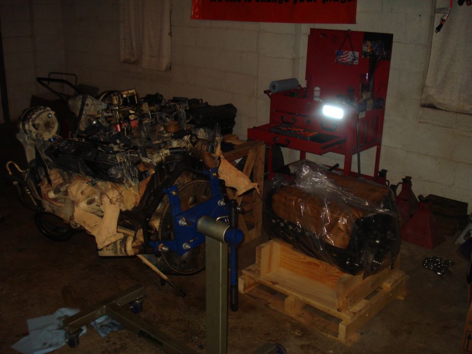 Disassembled engine on stand, another engine on pallet in workshop