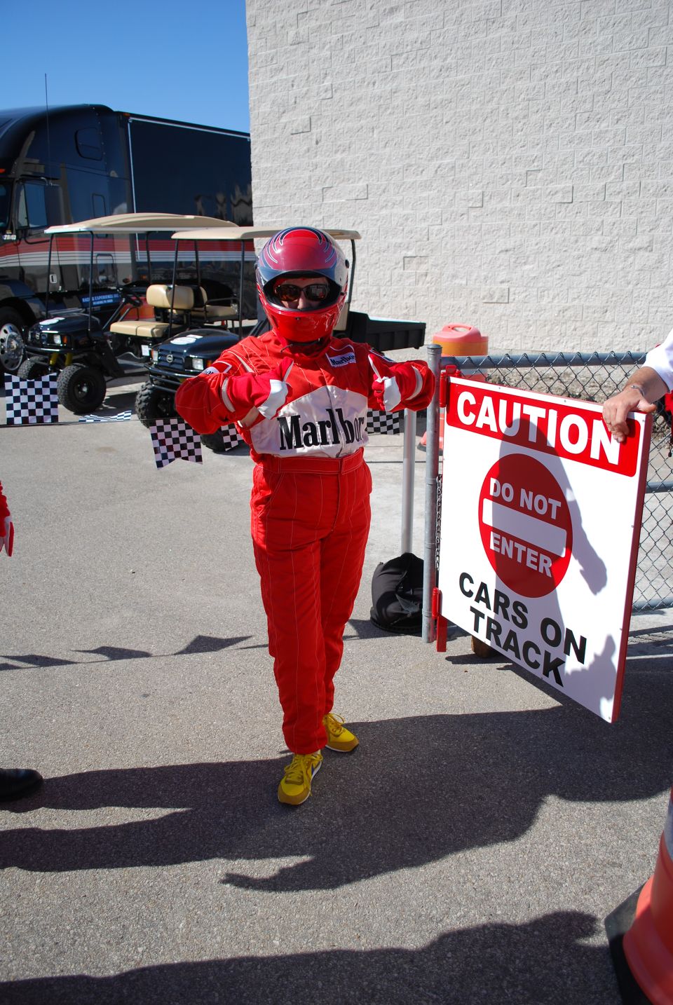 Person in red racing suit holding a flag with a cartoon character