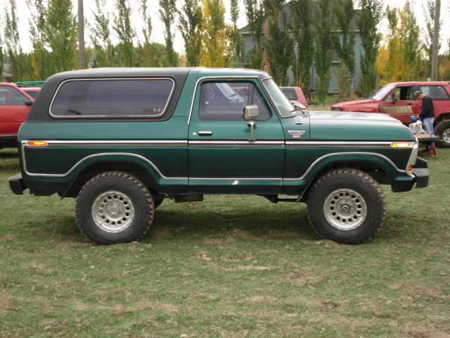 Green Ford Bronco SUV with black hardtop, side view on grass