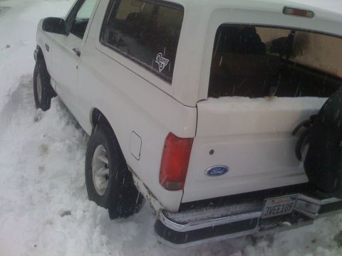 1979 Ford Bronco - This white Ford Bronco appears to be stuck in a snowy area, with its rear end visible and a license plate reading '3VEE109'.