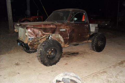 1980 Dodge Magnum - This damaged brown pickup truck, likely from the 1970s, has been modified with large off-road tires.