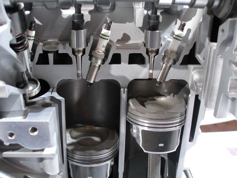 Engine cutaway with pistons and spark plugs visible