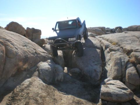 1997 Ford Ranger - A modified truck navigates a challenging rocky obstacle course under a clear blue sky.