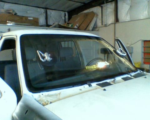 1993 Toyota 4Runner - The windshield is being removed from a vehicle, with a work light illuminating the interior.
