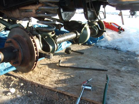 1989 Ford Bronco - Vehicle undercarriage components, including suspension and brakes, laid out on a tarp with tools nearby.