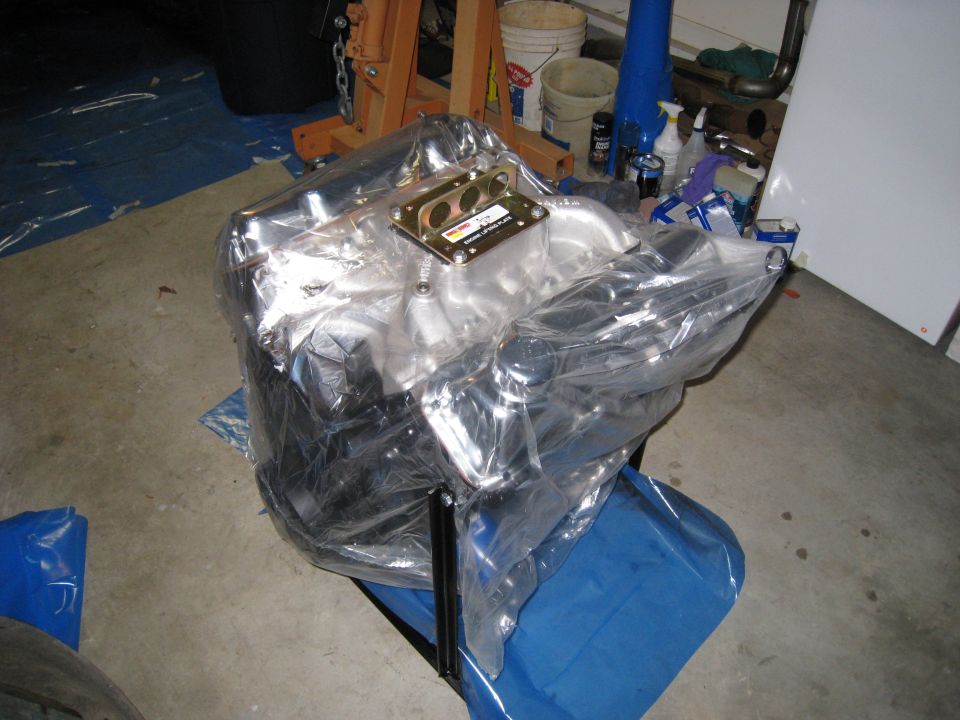 Engine covered in plastic wrap on a stand, with garage background