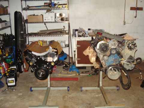 1984 Jeep J-10 - Two engines are displayed on stands in a garage setting, with storage shelves visible.