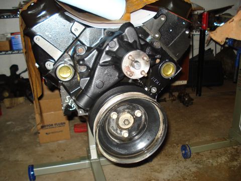 1984 Jeep J-10 - Close-up of an engine block assembly, the water pump and a large pulley, set up on an engine stand.