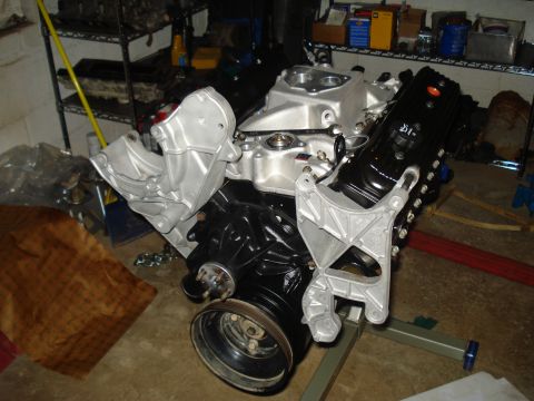 1984 Jeep J-10 - Engine assembly on a stand, a black block and silver intake manifold with visible text on the valve cover.