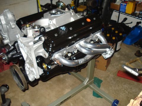 1984 Jeep J-10 - A rebuilt engine sits on a stand in a garage, ready for installation.