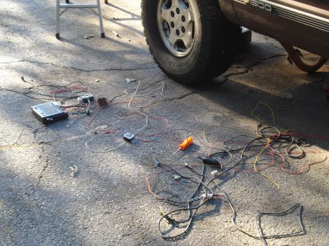 1984 Jeep J-10 - Wiring and electronic components are spread out on the ground next to a brown truck.
