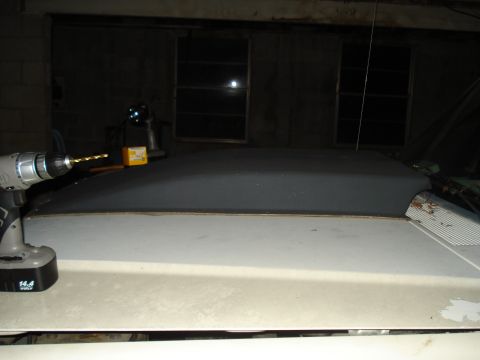 1991 Ford Bronco - A cordless drill with a bit is positioned over a section of a vehicle's roof, with a small yellow box nearby.