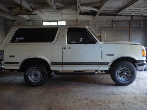 1991 Ford Bronco - Side profile of a white 1991 Ford Bronco, showing its distinctive body style and 4x4 badging.