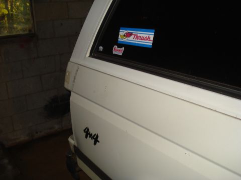 1991 Ford Bronco - Side view of a white SUV with '4x4' decal and window stickers.