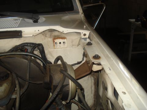 1991 Ford Bronco - Close-up view of the engine bay components in a white vehicle, showing the brake booster and various hoses and wiring.