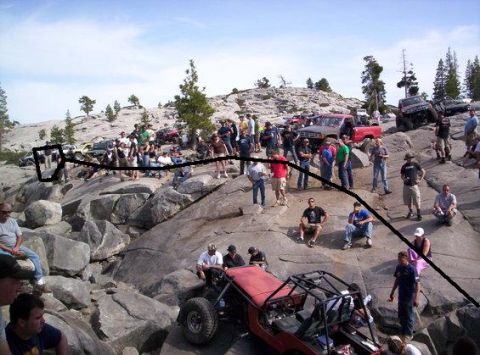 1989 Ford Bronco - Off-road enthusiasts and their vehicles congregate on a rocky landscape under a clear sky.