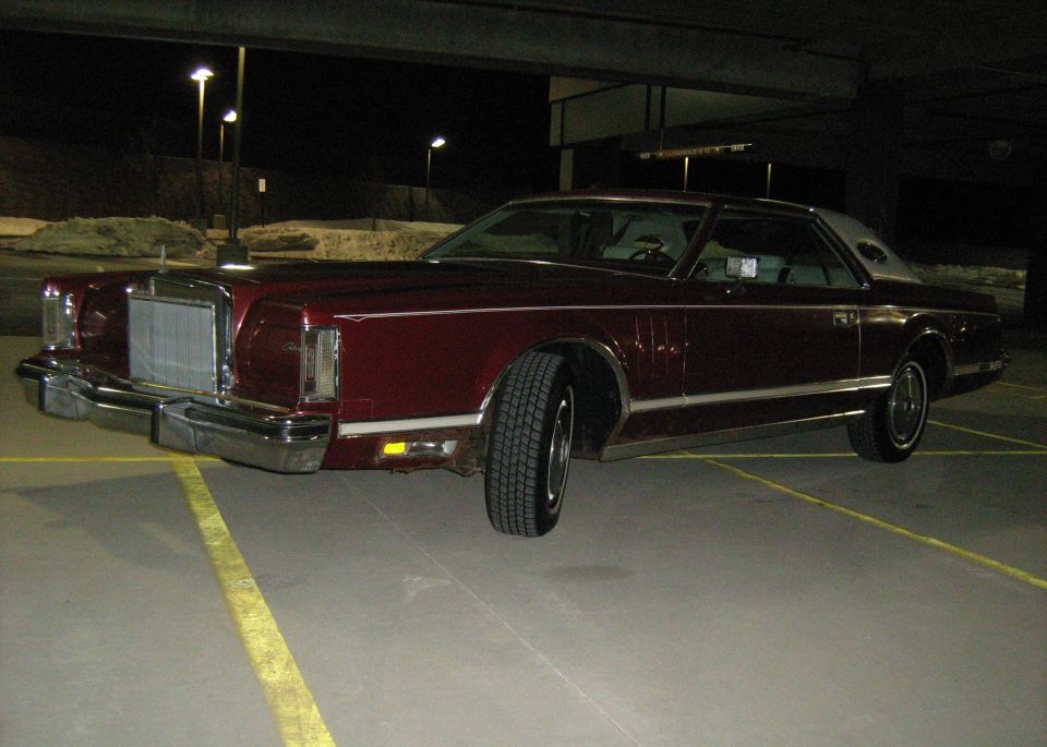 Dark red Lincoln Continental Mark V coupe in a parking garage at night