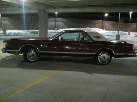 1988 Mercury Grand Marquis - A side profile of a classic Lincoln Continental Mark VI coupe parked in an indoor lot at night.