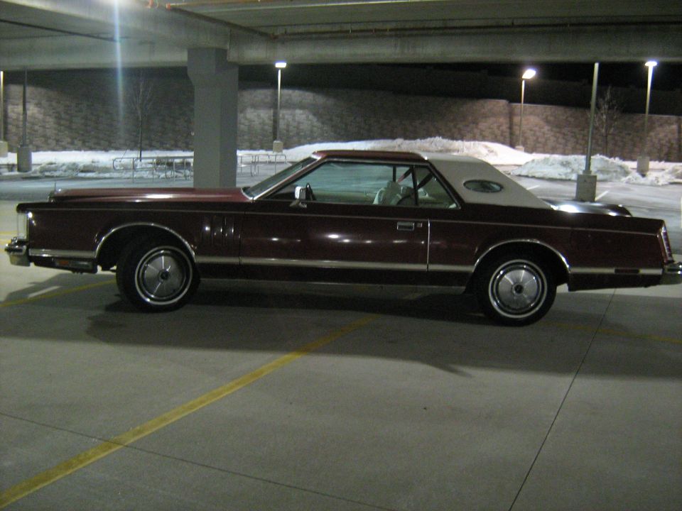 Maroon Lincoln Continental Mark VI coupe with a white vinyl top parked in a garage