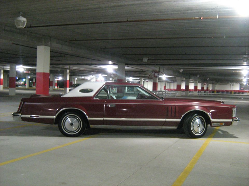 Maroon Lincoln Continental Mark V parked in a garage