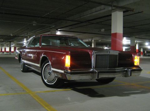 1988 Mercury Grand Marquis - Maroon coupe with white vinyl top parked in a parking garage, showing its front grille and headlights.