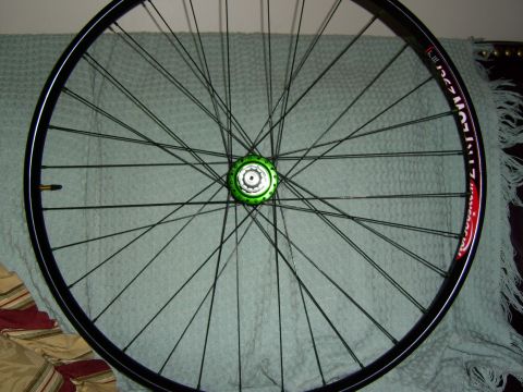 1972 Ford Ranchero - A bicycle wheel with a green hub and black spokes is shown against a textured background.