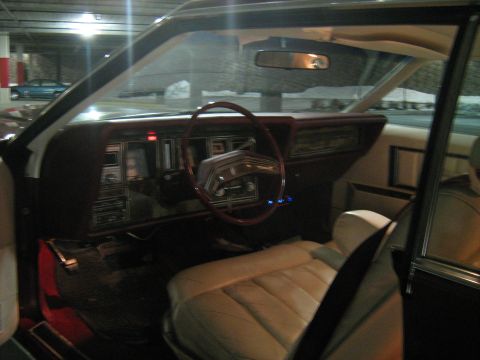 1988 Mercury Grand Marquis - Interior view of a car, showing the dashboard, steering wheel, and seats. Another vehicle is seen through the window.