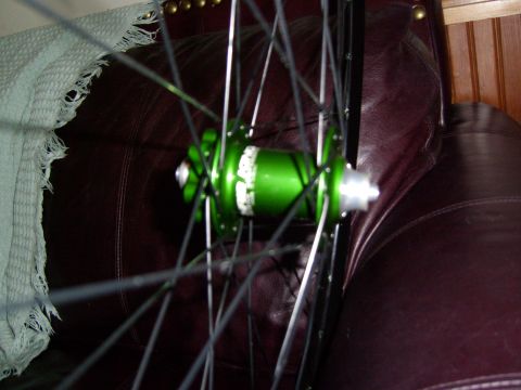 1972 Ford Ranchero - A close-up view of a green bicycle wheel hub with spokes, set against a dark leather background.