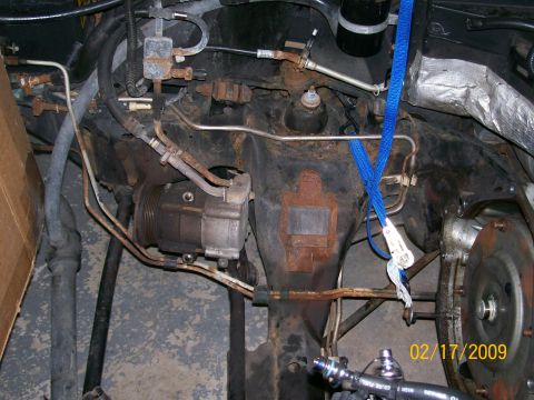 1995 Mercury Grand Marquis - Close-up view of engine bay parts, showing an AC compressor and various hoses, with a blue strap.