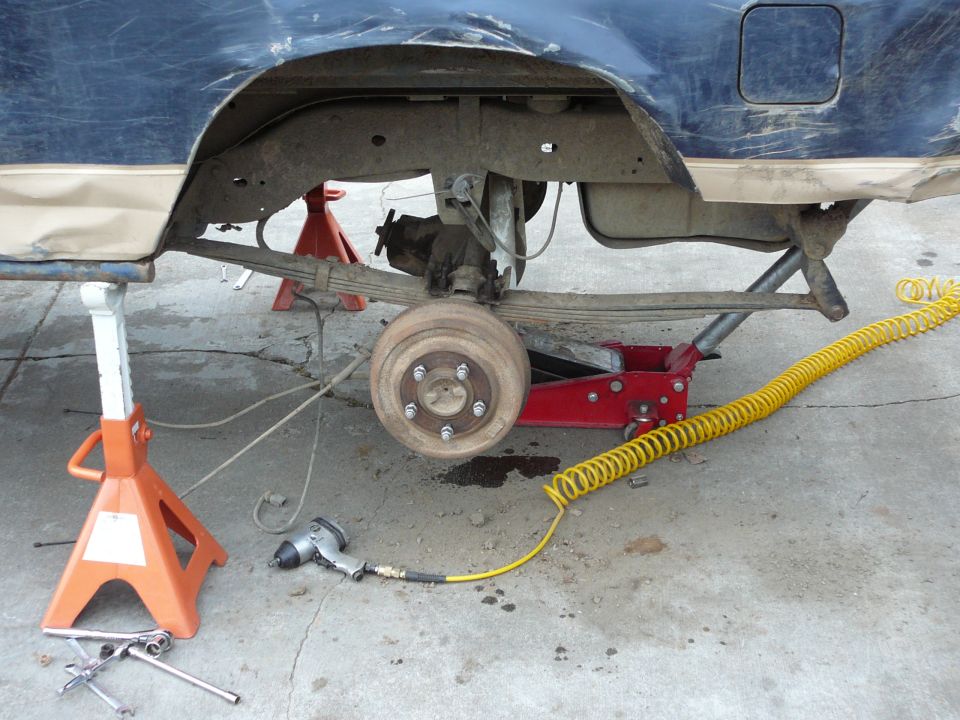 1991 Ford Bronco rear axle and leaf spring suspension on jack stands with an impact wrench nearby