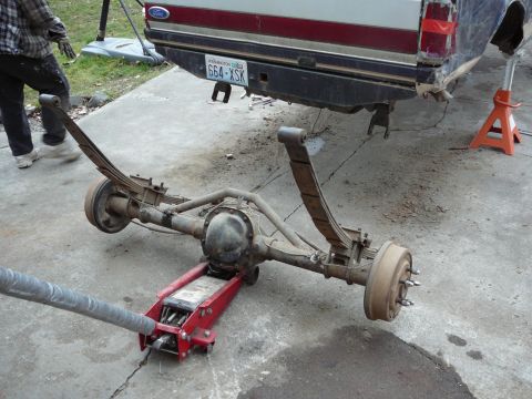 1991 Ford Bronco - A rear axle assembly is being worked on, with the vehicle's rear end elevated on jack stands.
