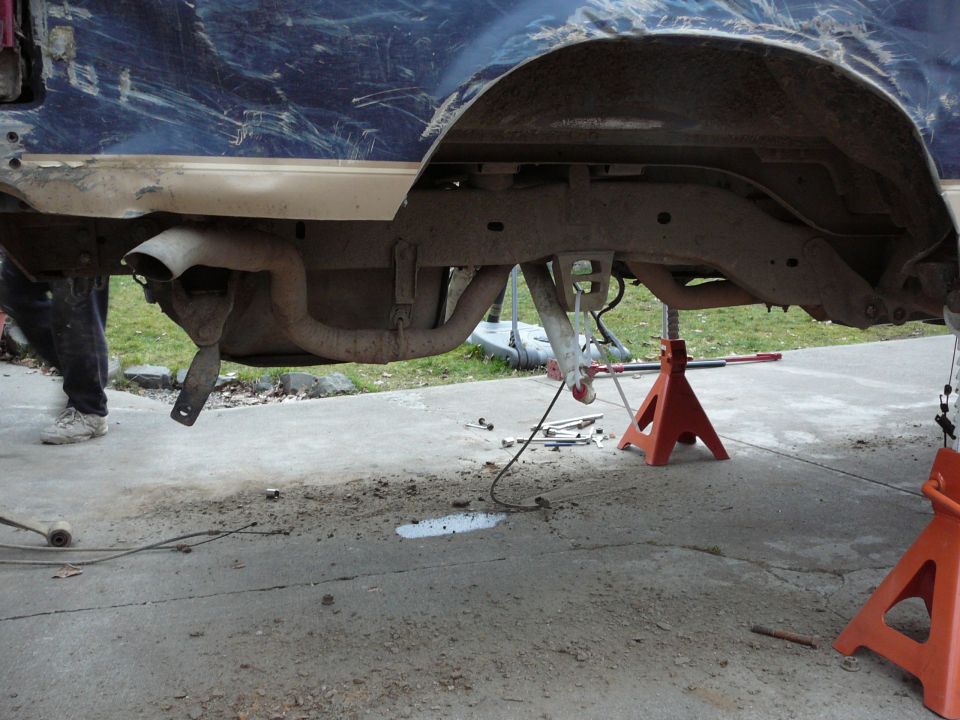 Rear axle and exhaust of a blue vehicle on jack stands