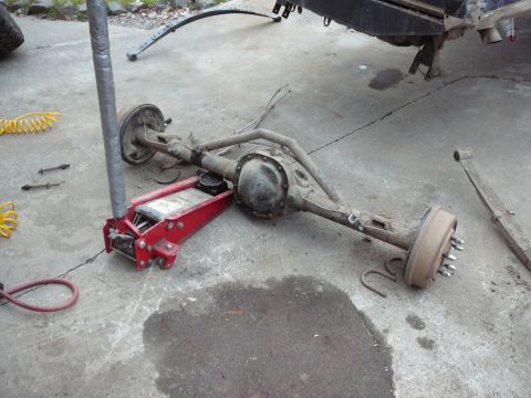 1991 Ford Bronco - Rear axle assembly removed from a vehicle and supported by a jack on a concrete surface.