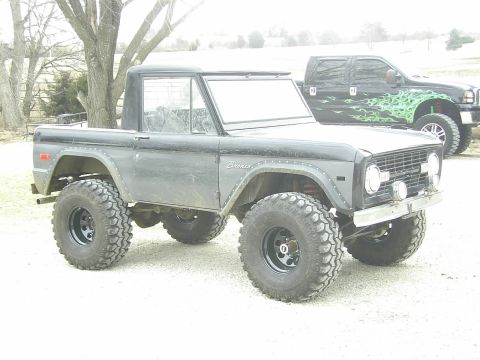 1978 Ford Bronco - This lifted 1978 Ford Bronco is parked outdoors next to a black pickup truck.