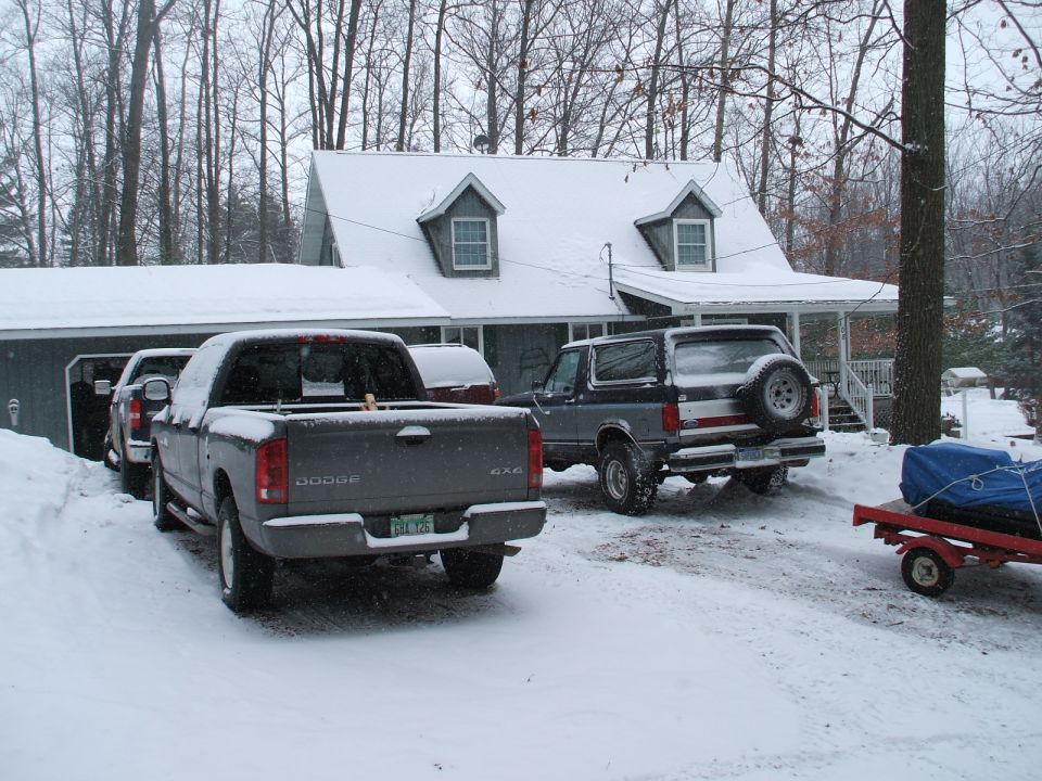 Gray and blue Ford Bronco with a spare tire on the back, parked in snow