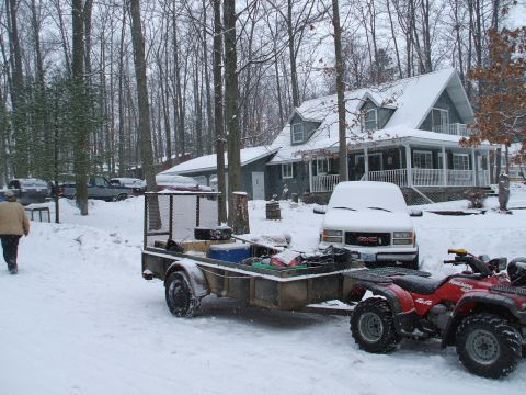1990 Ford Bronco - A red ATV and utility trailer sit in the snow outside a house, with a white GMC van parked nearby.