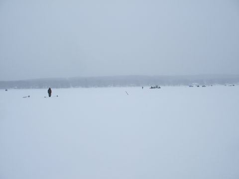 1990 Ford Bronco - Several individuals are spread out on a vast, snow-covered expanse, engaged in ice fishing activities.