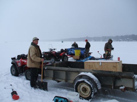1990 Ford Bronco - People and ATVs are gathered on a frozen body of water with a trailer and equipment.