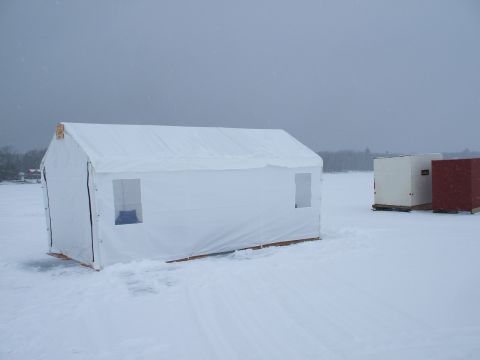 1990 Ford Bronco - Ice fishing shelters sit on a frozen body of water during a snowfall.
