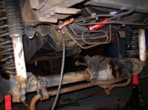 1986 Ford Bronco - Close-up of vehicle undercarriage, focusing on suspension and drivetrain parts.