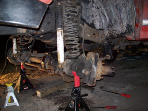 1986 Ford Bronco - Close-up view of a vehicle's rear axle and suspension system, elevated on jack stands.