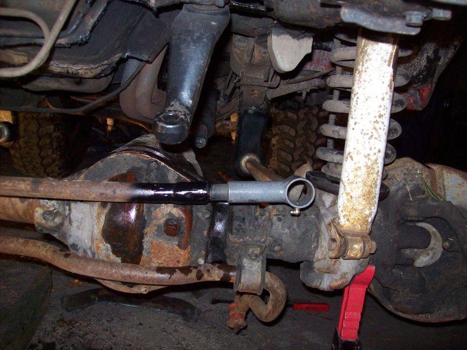 Close-up of front suspension and steering linkage with a red jack stand