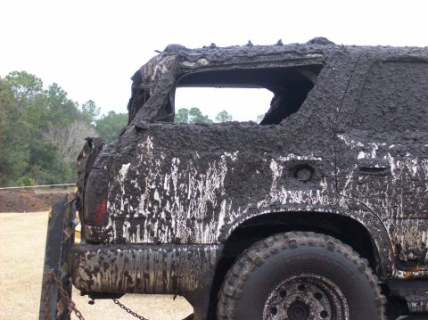 1986 Ford Bronco - This heavily mud-covered SUV shows its rear quarter panel and taillight, with significant damage to the rear window area.