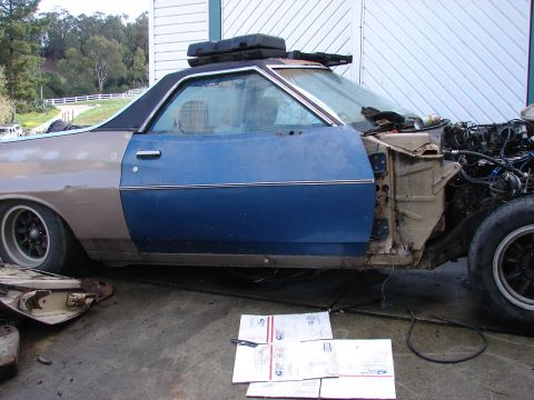 1973 Ford Ranchero - A partially disassembled Ford Ranchero sits outdoors, showing its interior and engine bay.