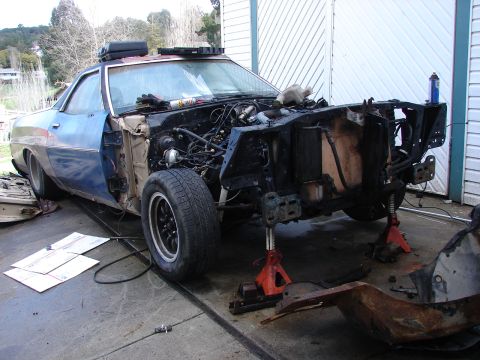 1973 Ford Ranchero - A 1973 Ford Ranchero is shown disassembled and on jack stands, with its front end open to reveal the engine compartment.