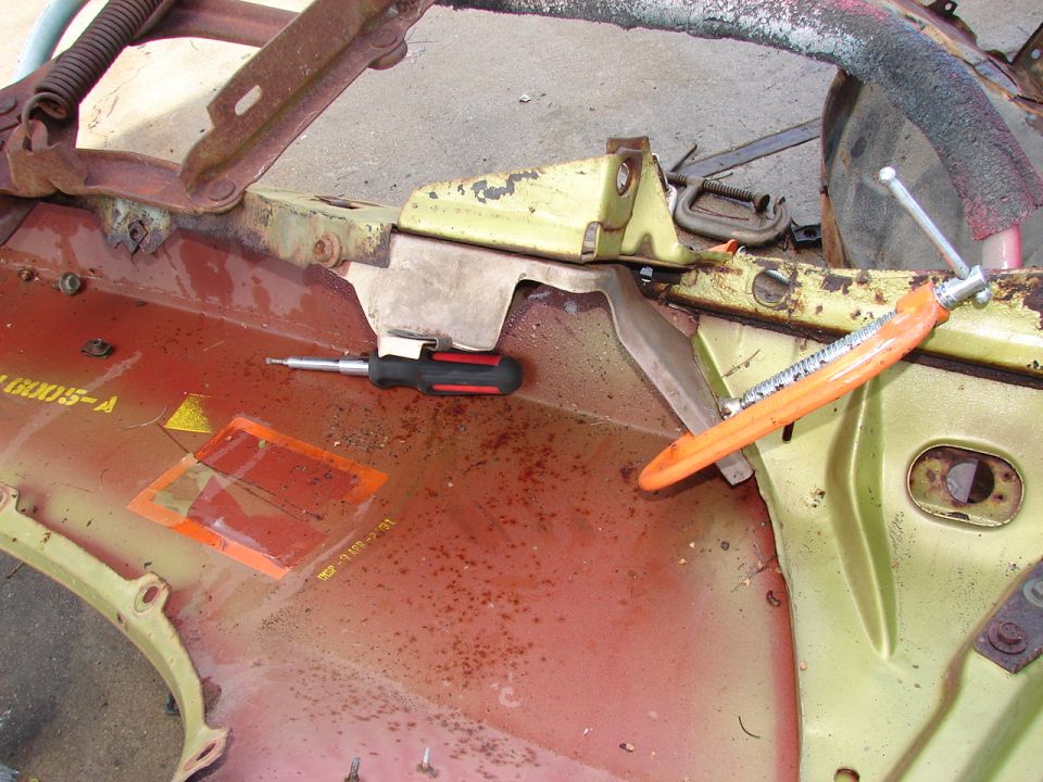 close-up of rusty car body panel with a screwdriver and clamp